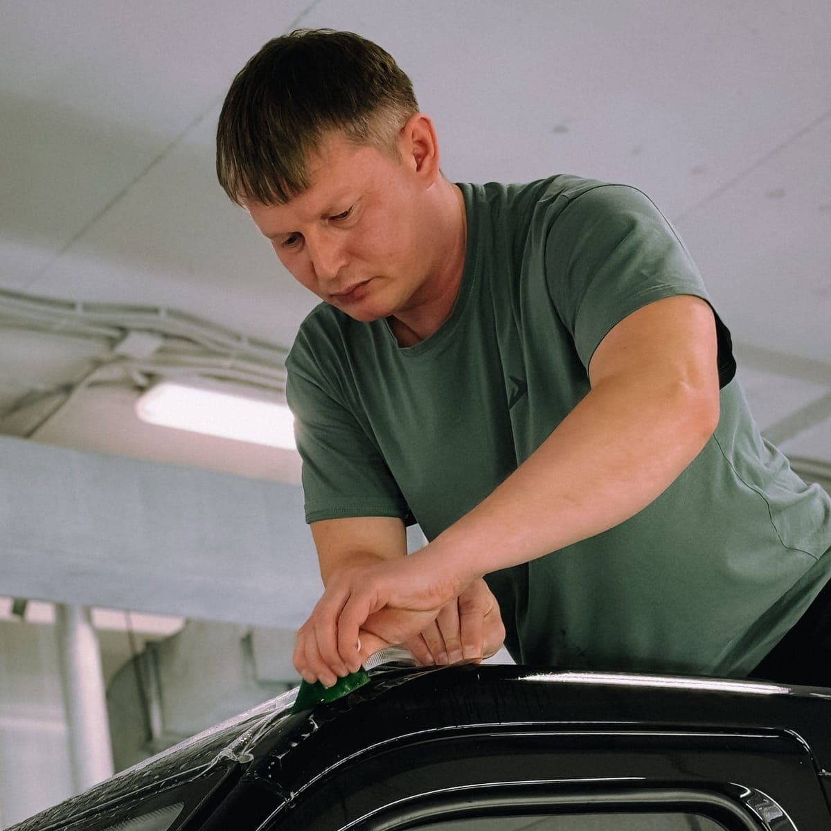 Tint film being laid onto a rear side window in the bay.