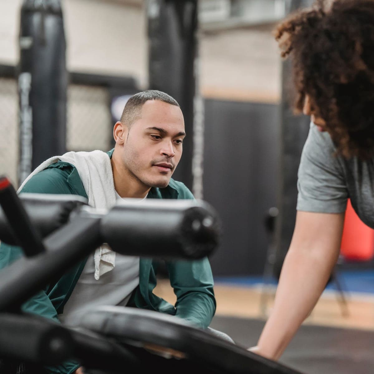 A coach guiding a client through a dumbbell set.