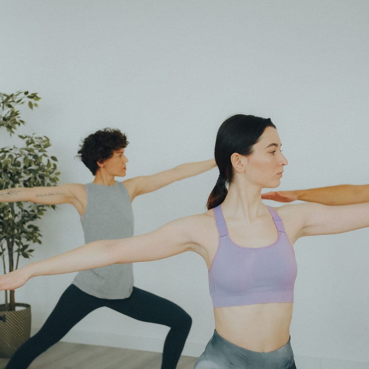 Two clients holding warrior pose in the yoga room.