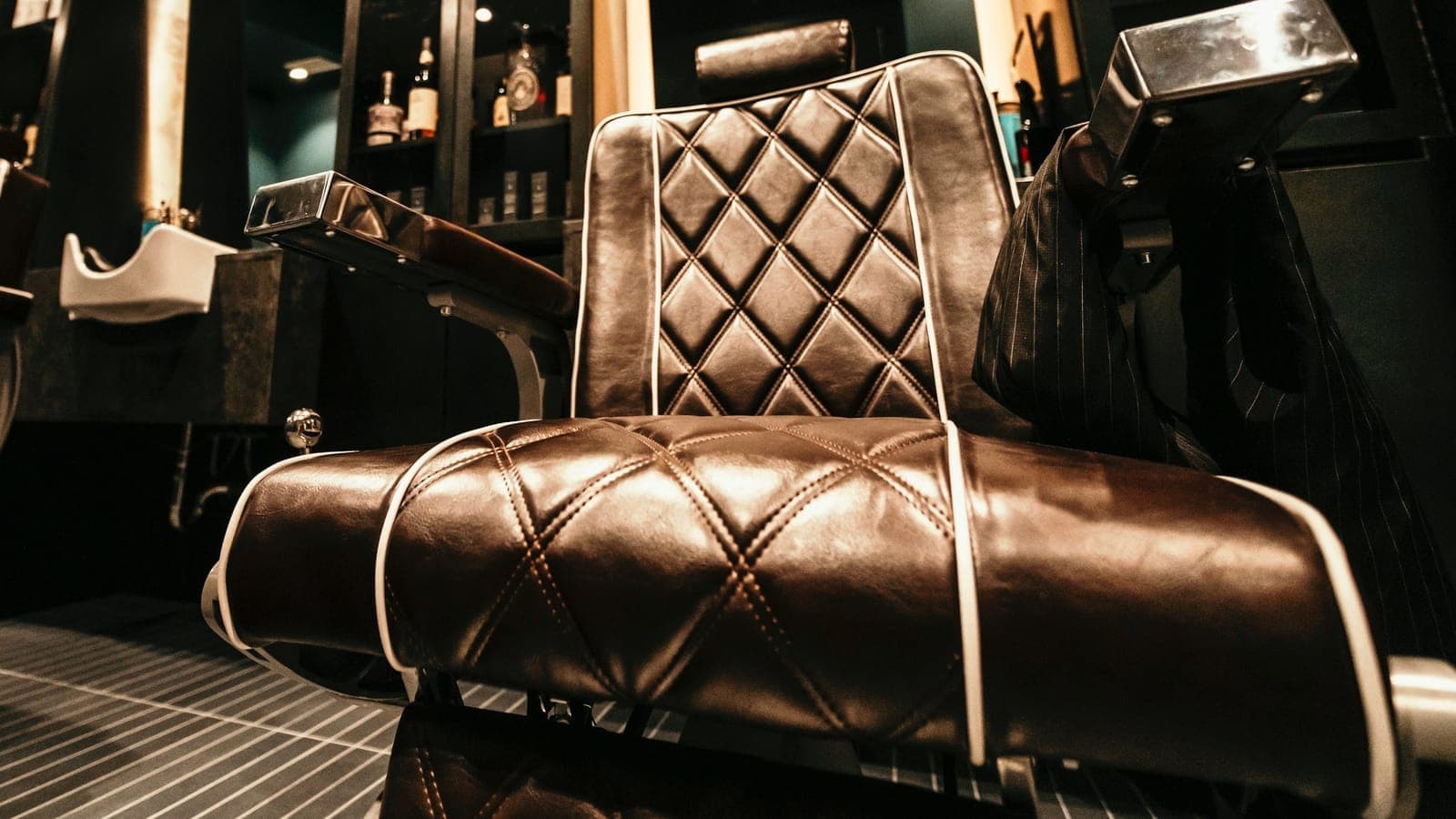An empty leather barber chair in a dimly lit barbershop
